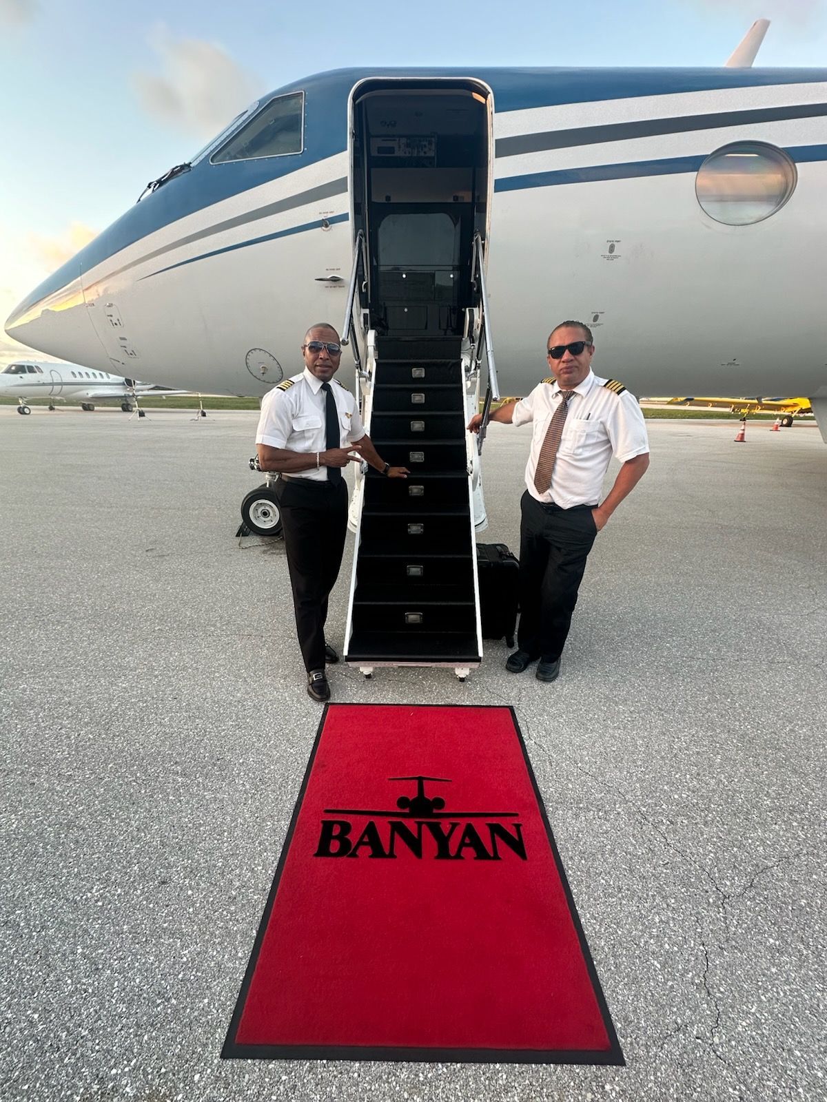 Two pilots are standing in front of a private jet.