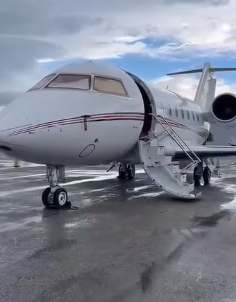 A private jet is parked on the tarmac at an airport.