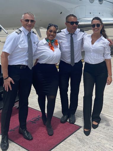 A group of people posing for a picture in front of a plane.