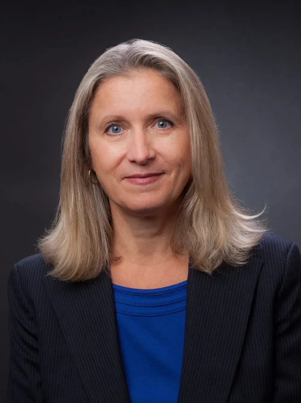 A woman is wearing a blue shirt and a black jacket.