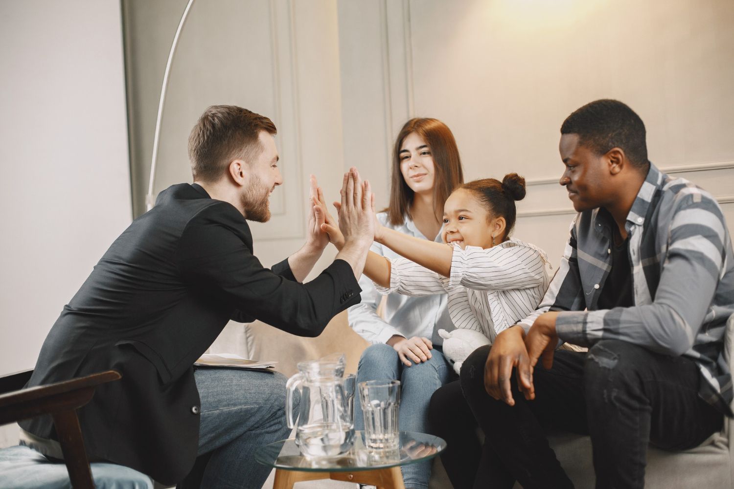 A family and therapist high-five in a brightly lit room.