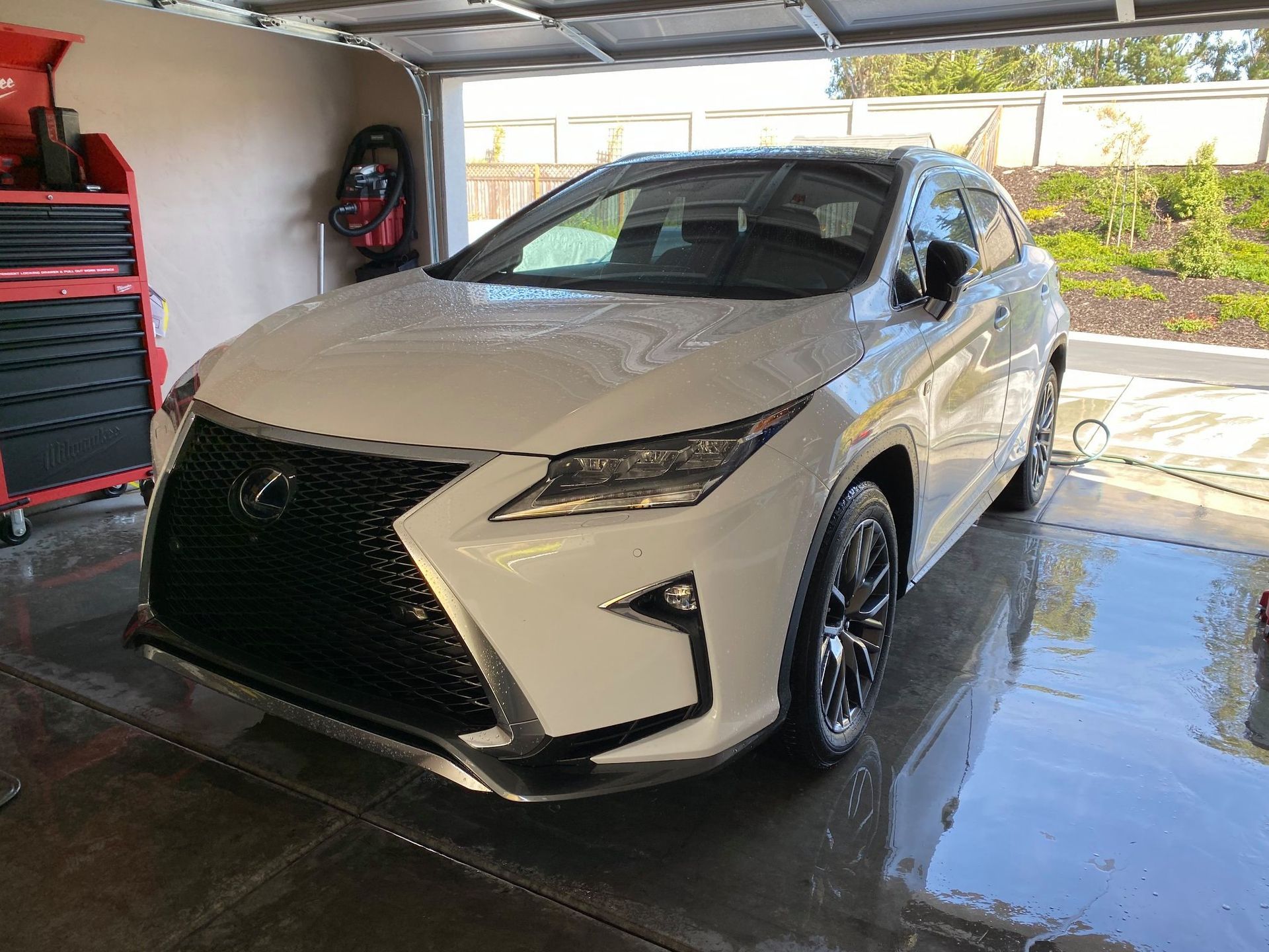 White Lexus SUV parked in a garage, front view with large black grille and wet concrete floor
