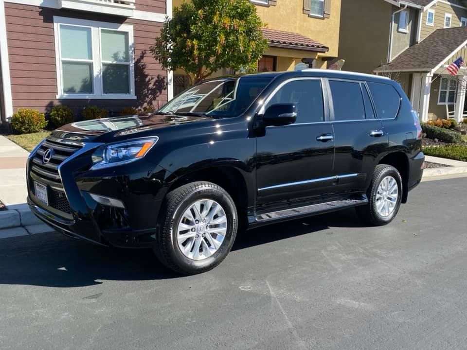 Black SUV parked in a driveway in front of a suburban house.