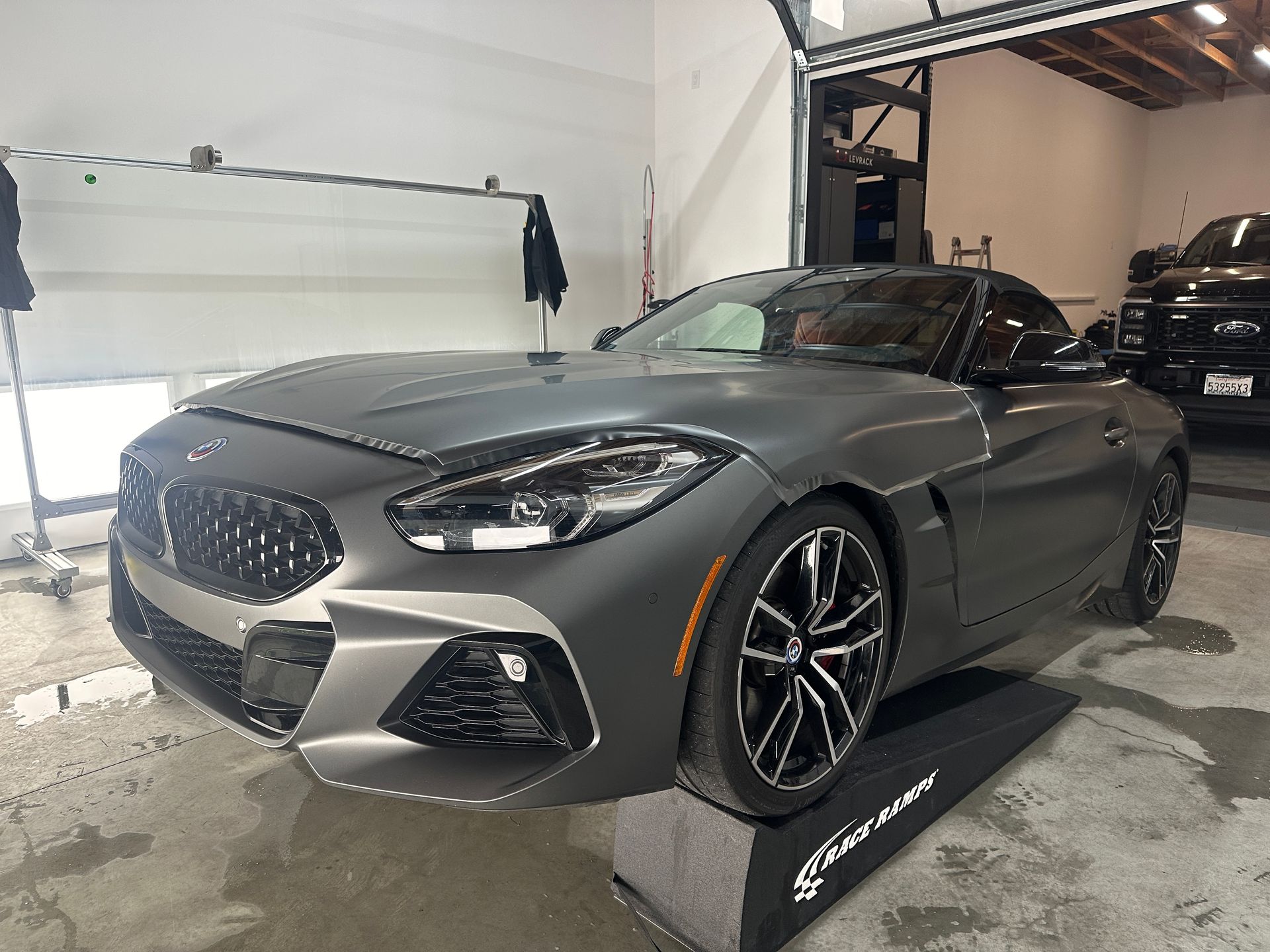 Gray convertible sports car in a garage, front three-quarter view on a display ramp