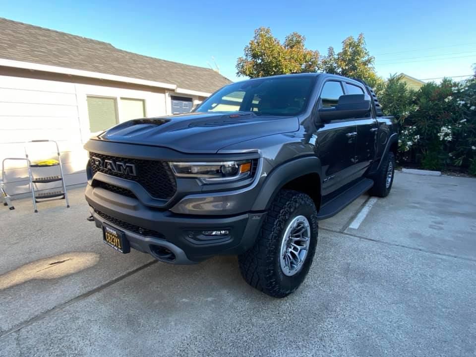 Black RAM pickup truck parked in a driveway beside a garage on a sunny day
