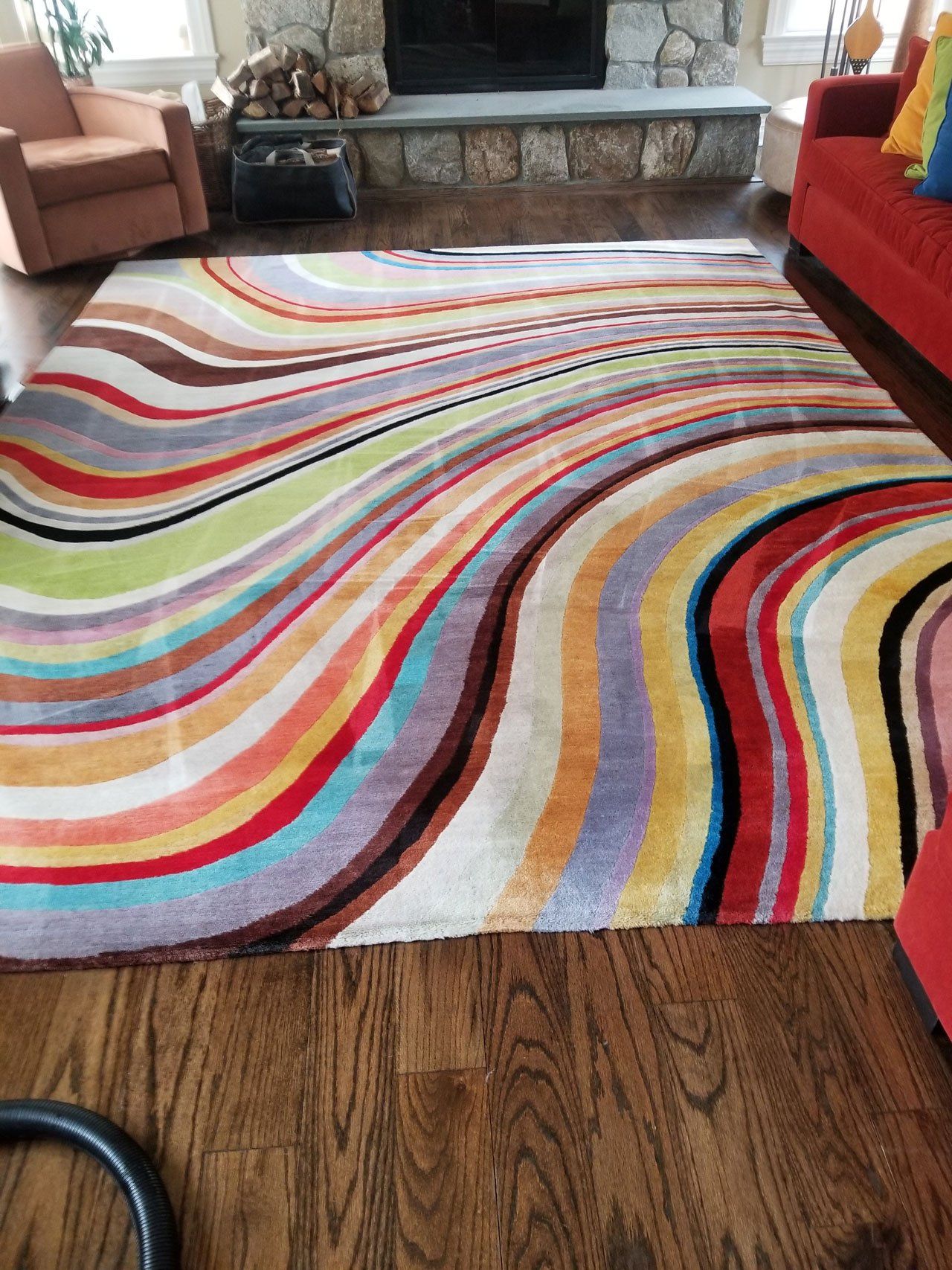 A large, rectangular area rug with colorful, wavy stripes featuring red, yellow, blue, green, and purple in a living room.