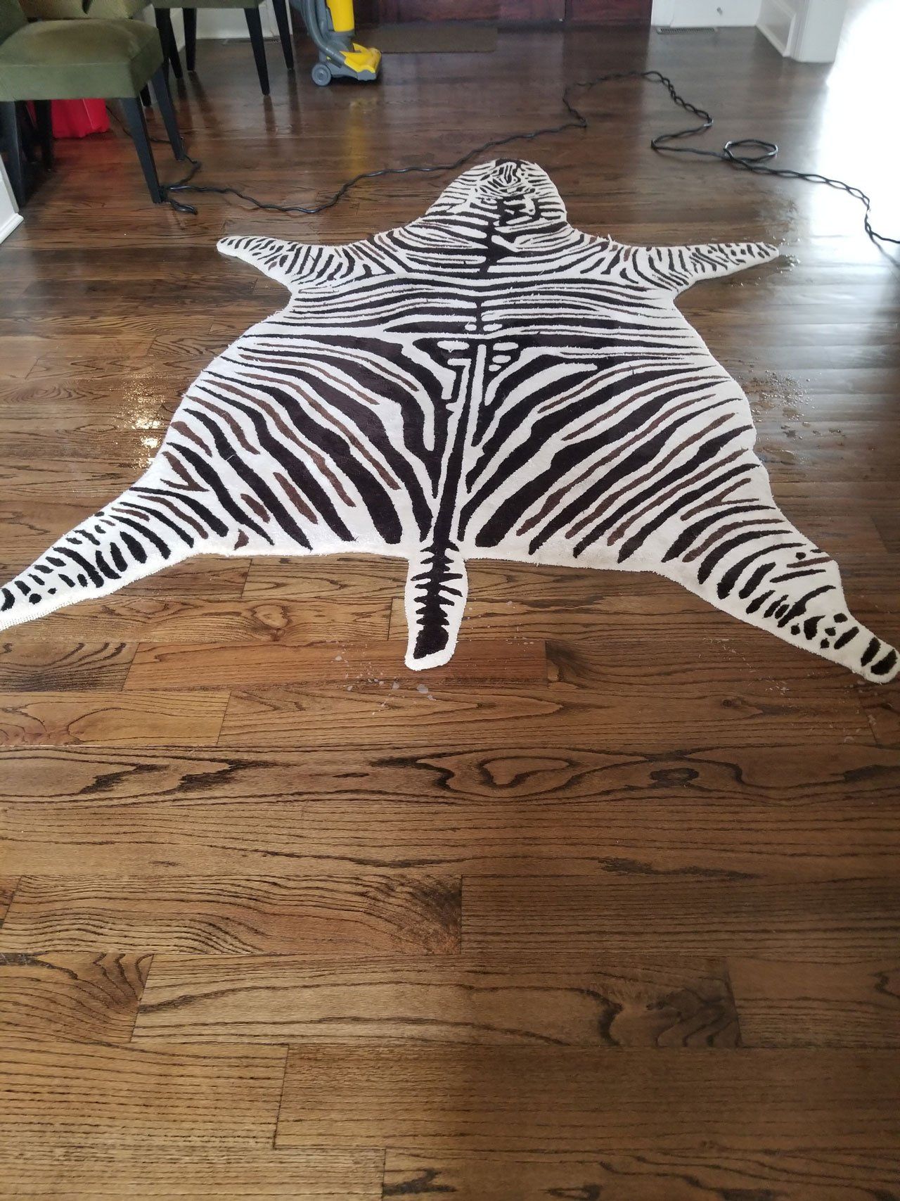 A black-and-white zebra-patterned area rug laid out on a dark wood floor.