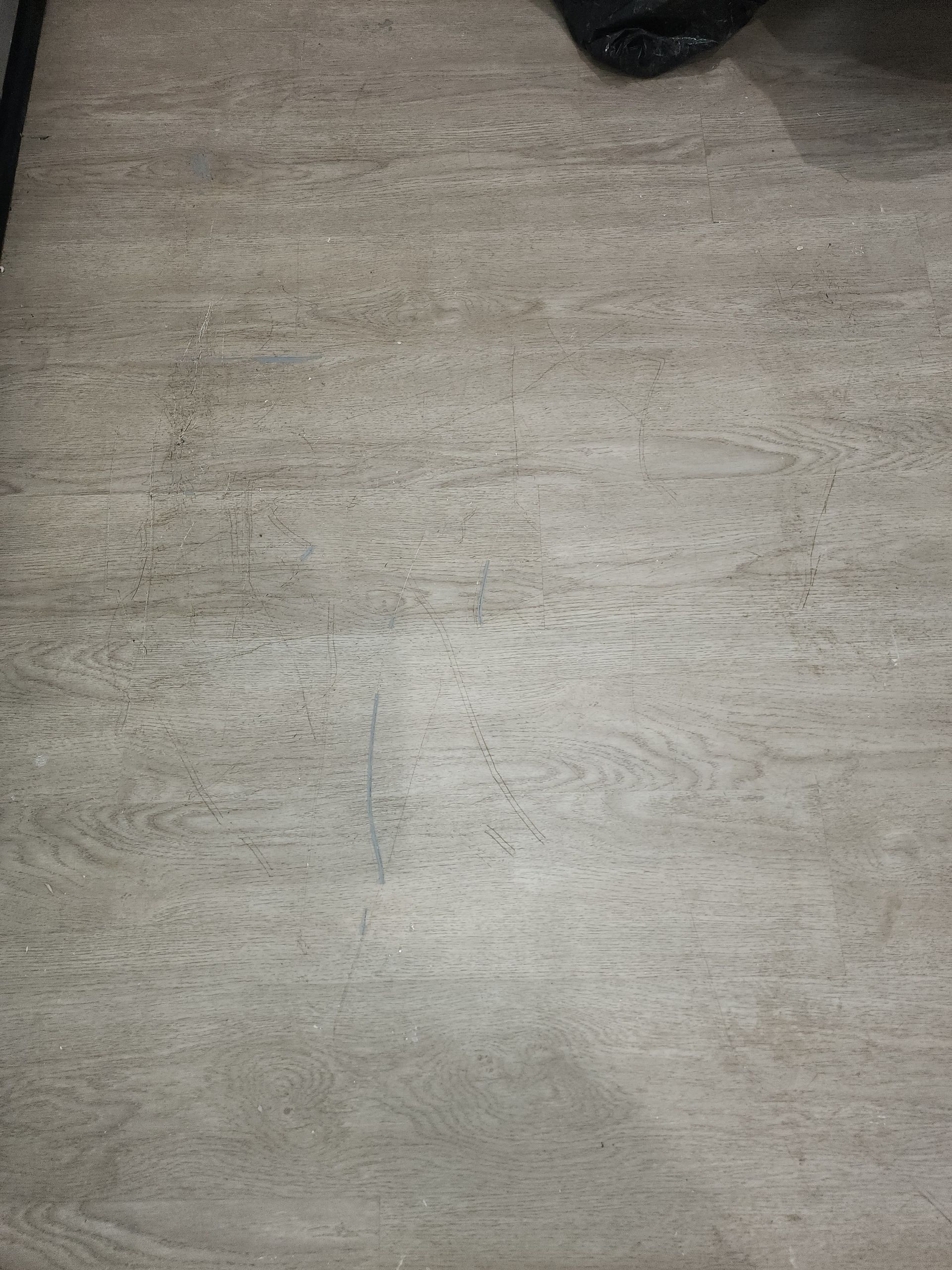 A close-up view of light gray, wood-grain textured flooring.