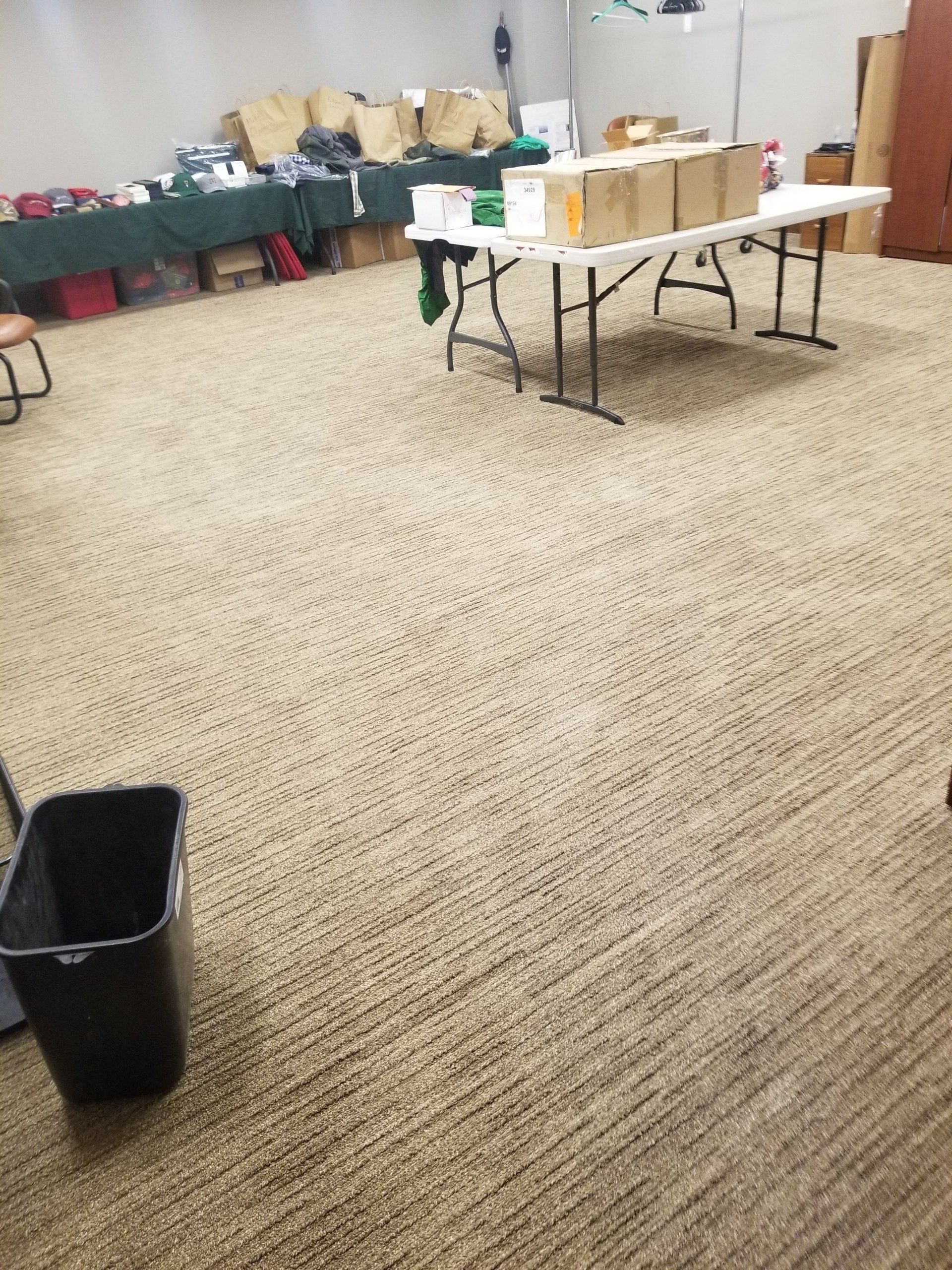 A room with tables covered in supplies, boxes, and bags, set up for an organized distribution or event.