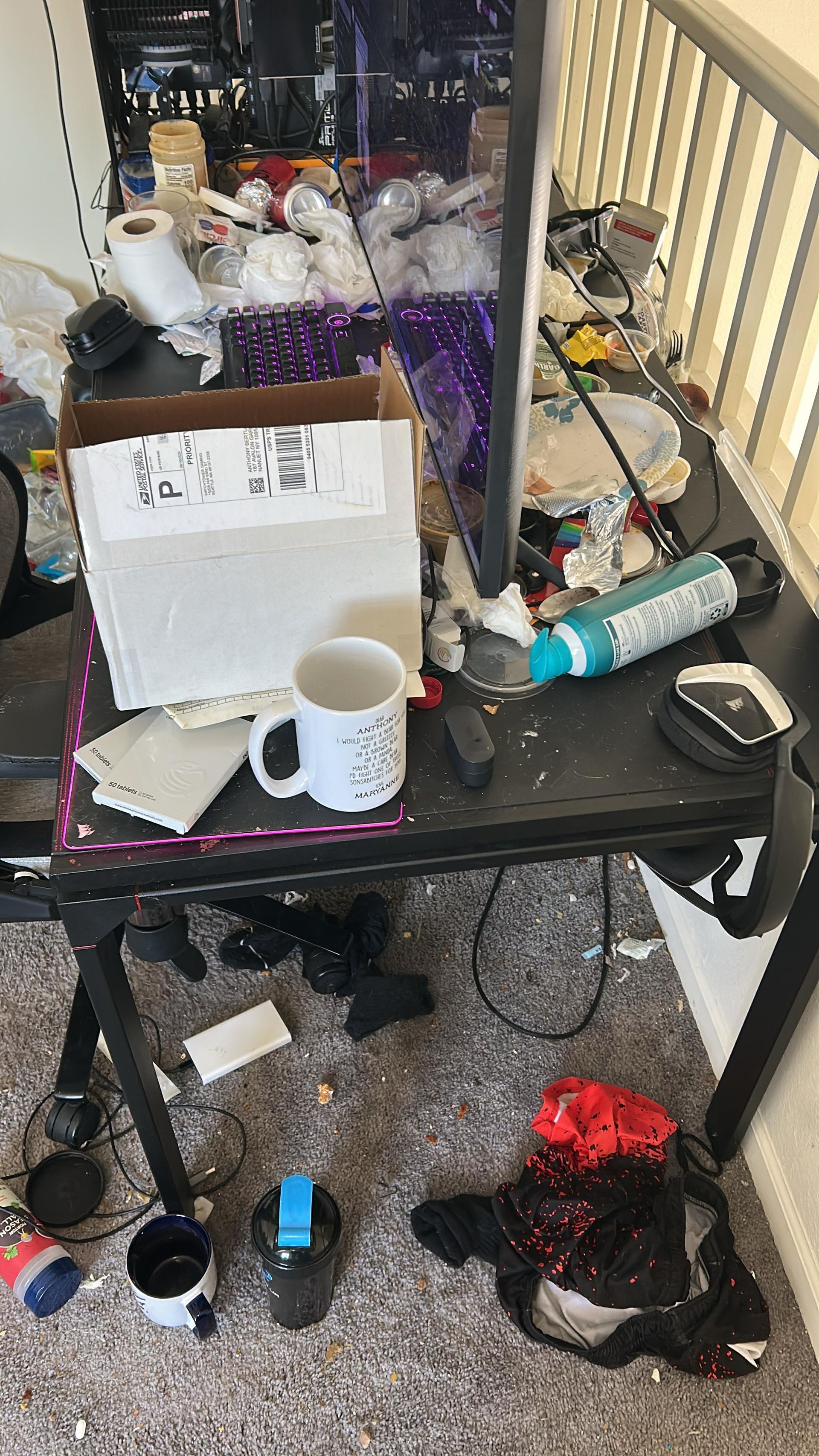 A cluttered desk with a white box, mug, and various items, plus scattered debris on the carpeted floor below.