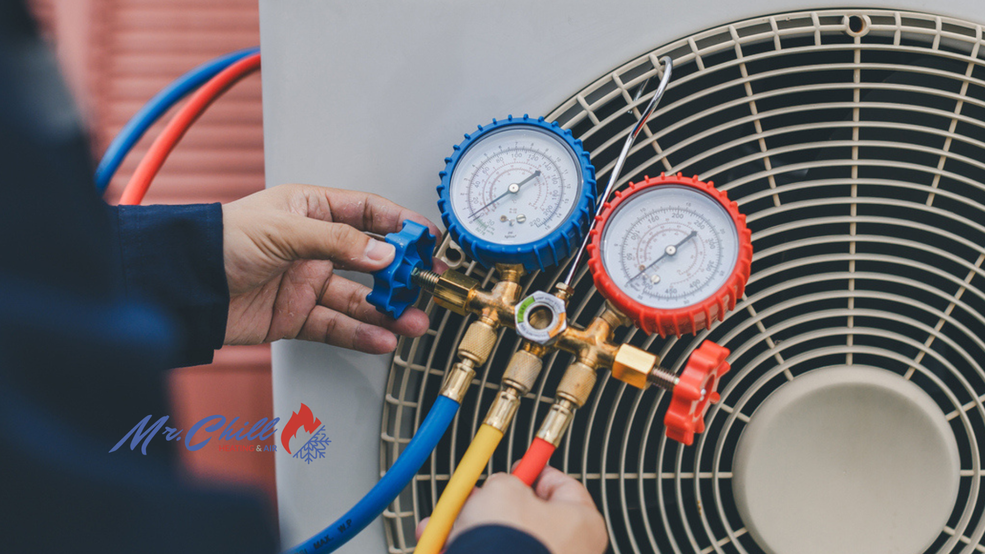 Technician connecting gauges to an outdoor HVAC condenser unit for maintenance