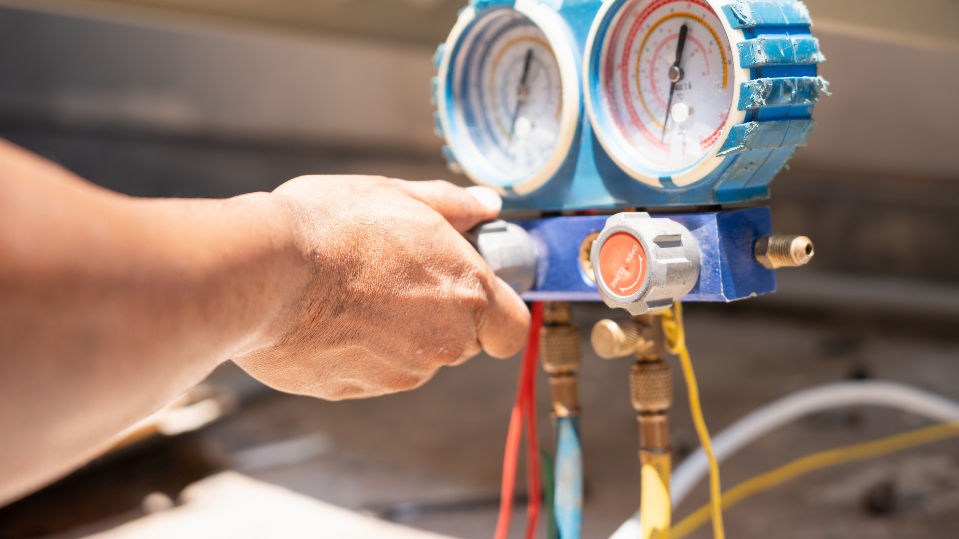 Person tightening a blue pressure gauge on pipes with a wrench