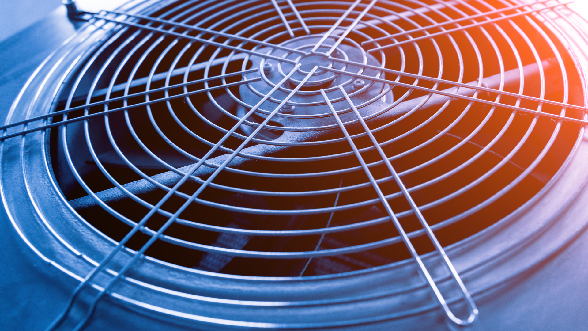 Close-up of a circular metal fan grill with blue and red lighting on an air conditioner unit