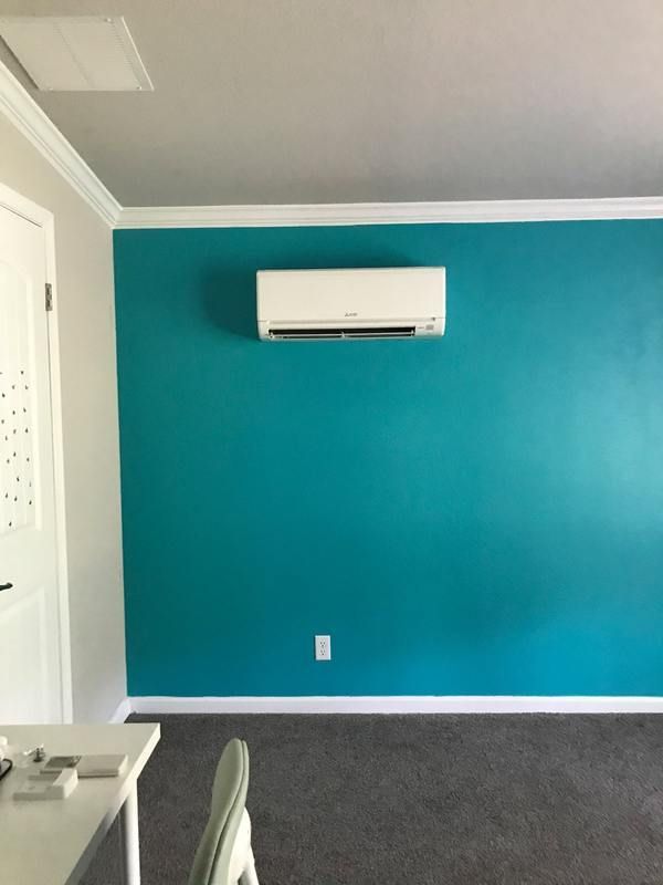 Teal wall with white AC unit. White trim, door, and ceiling. Gray carpet.