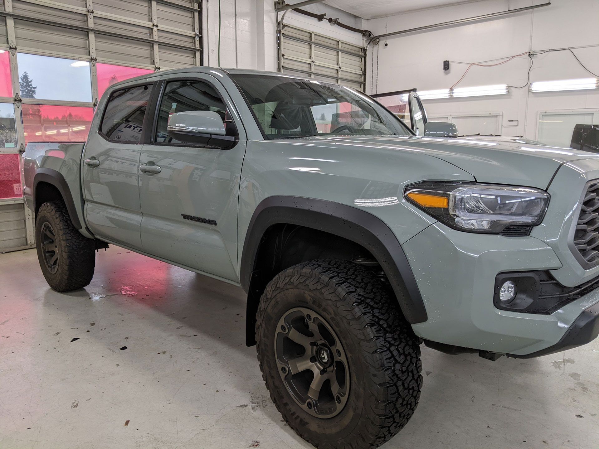 Gray pickup truck with off-road tires parked inside a garage