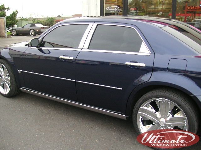 Dark blue sedan with chrome trim parked beside a building on a street.