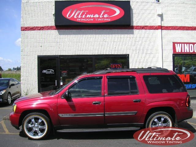 Red SUV parked in front of an auto body shop with an “Ultimate” sign.