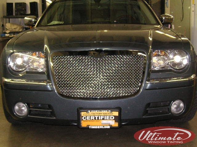 Front view of a black sedan with a chrome grille and yellow certified license plate indoors
