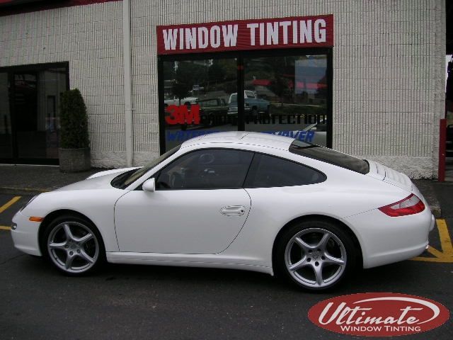 White sports car parked outside a window tinting shop.
