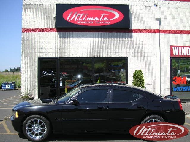 Black sedan parked outside Ultimate Auto shop with a red sign above the entrance