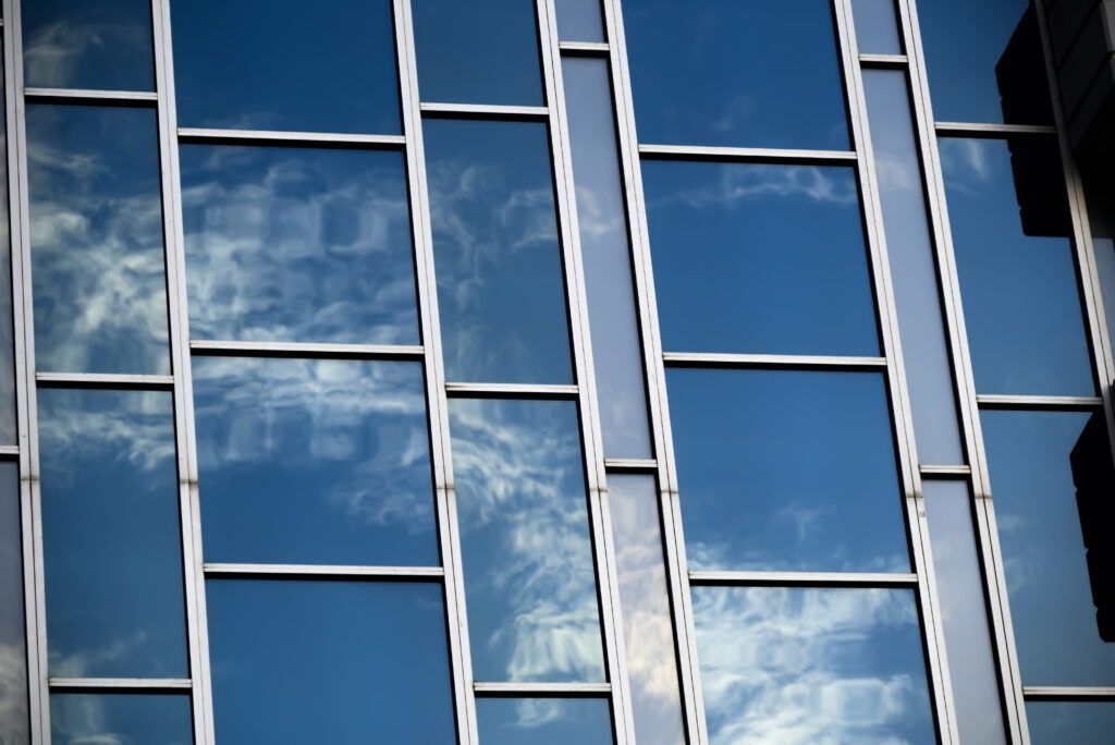 Glass building windows reflecting blue sky and clouds