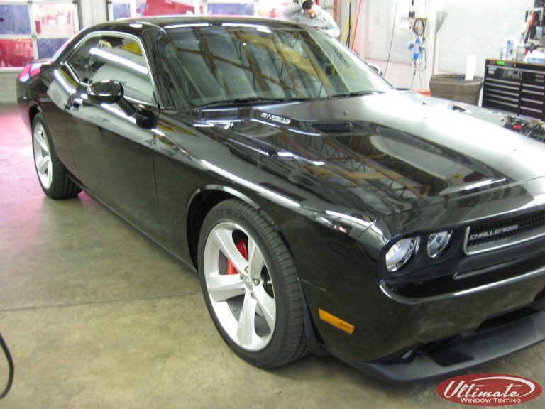 Black Dodge Challenger parked indoors in a garage, shown from the front-left side.