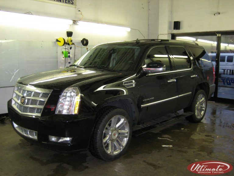 Black Cadillac Escalade in a garage, viewed from the front-left side.