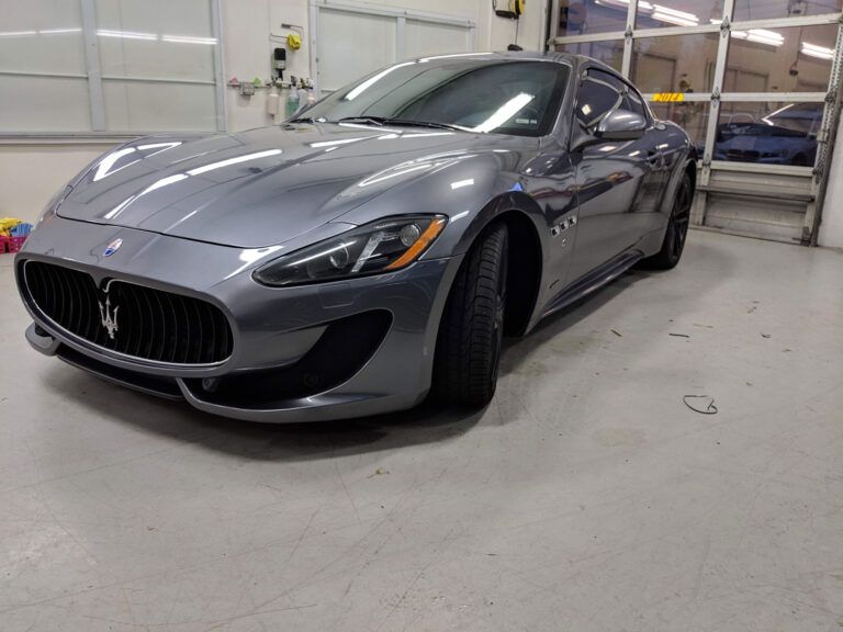 Gray Maserati sports car in a garage, viewed from the front-left side.