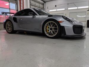 Silver sports car in a garage, low-angle side view with yellow brake calipers and gray wheels