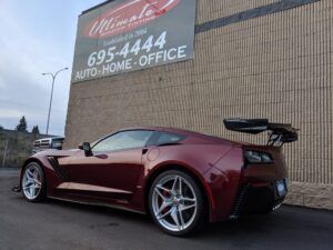 Red sports car parked beside a tan building with a sign reading 695-4444 AUTO HOME OFFICE.
