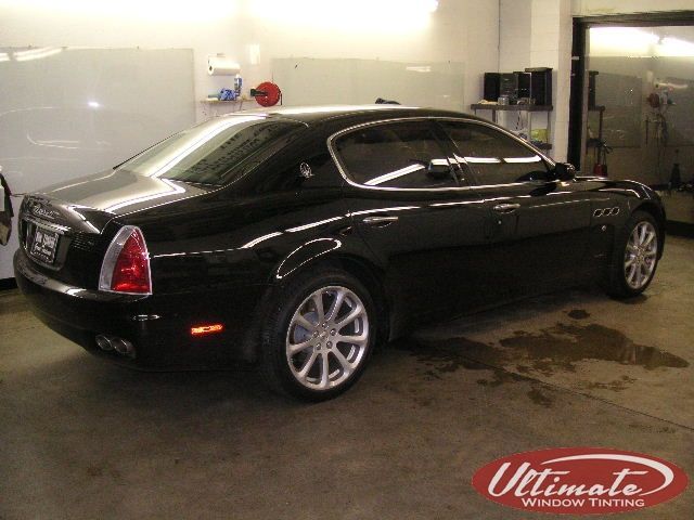 Black luxury sedan parked indoors in a garage, side view.