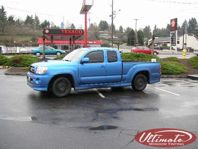 Blue pickup truck parked at a wet gas station lot with a Texaco sign in the background