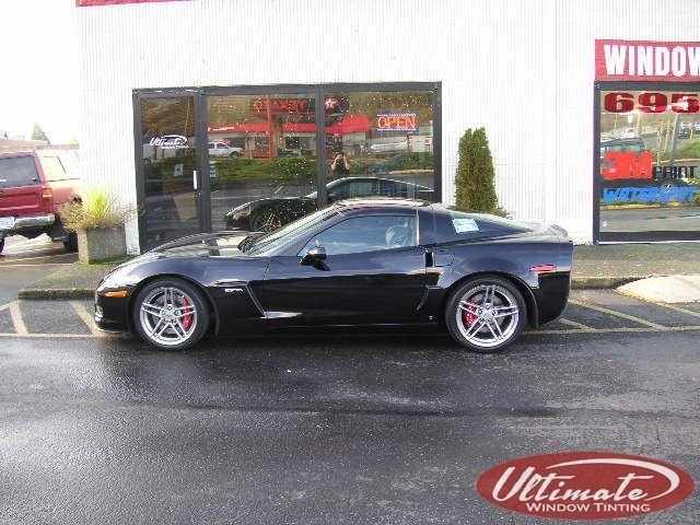 Black sports coupe parked outside an auto shop storefront