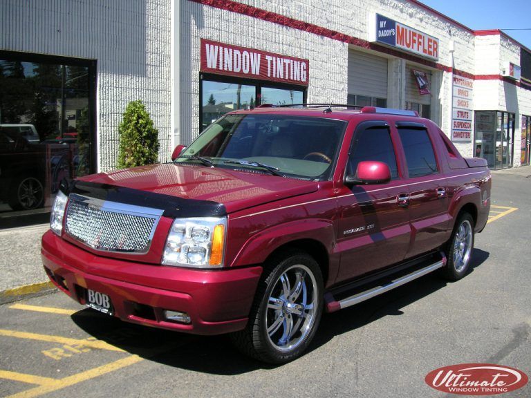 Maroon pickup truck parked outside a storefront, with chrome grille and tinted windows