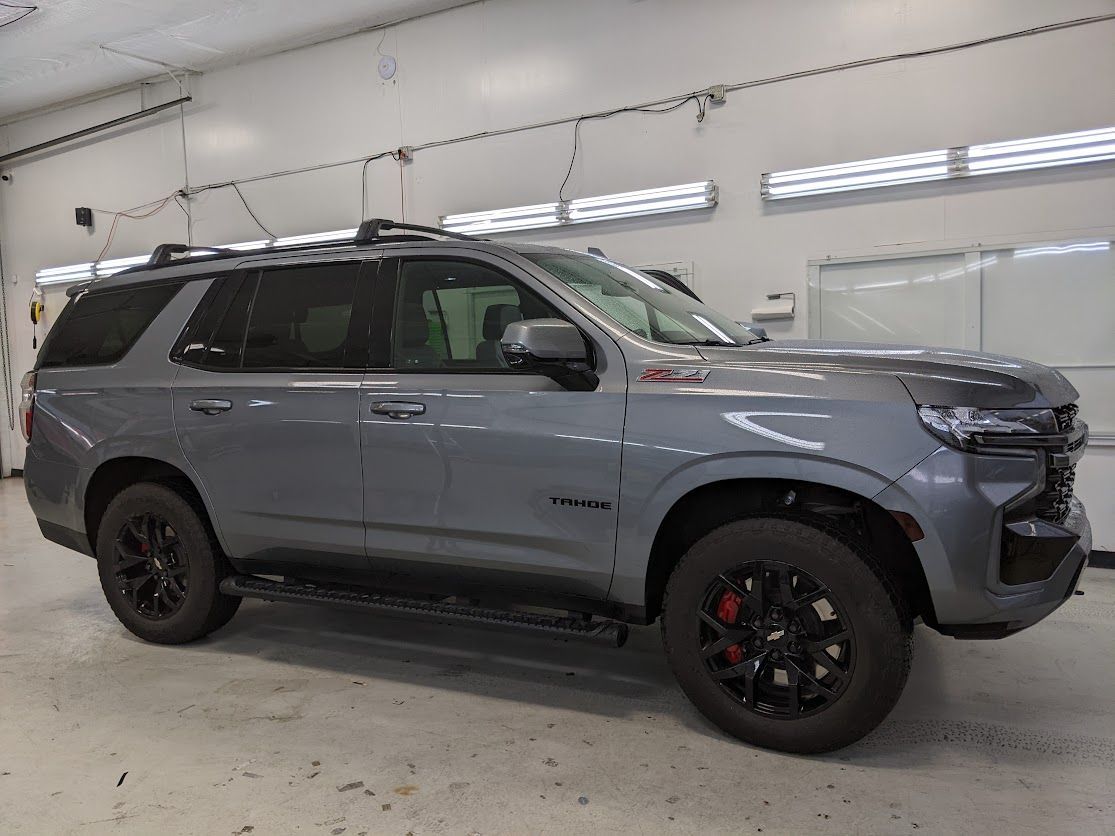Gray SUV with black wheels parked inside a white auto body shop garage