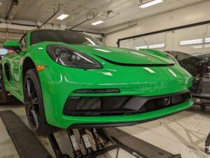 Bright green sports car in a garage on a lift with wheels removed