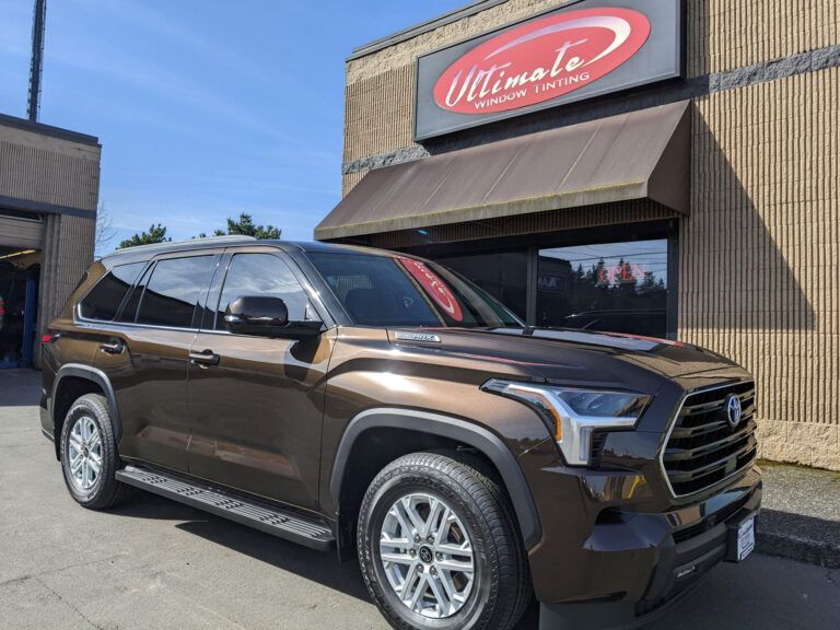 Brown SUV parked outside a building with a red “Ultima” sign