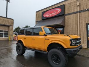 Orange off-road SUV parked outside a building on a rainy day