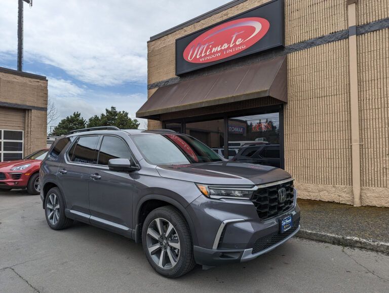 Gray SUV parked outside a building with a red oval sign above the entrance