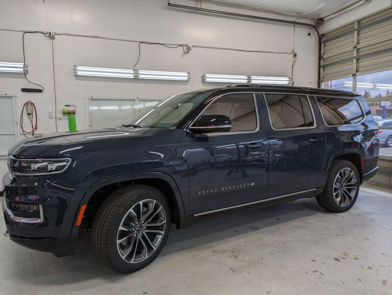 Dark blue SUV parked inside a garage, viewed from the front-left side.