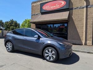 Gray electric car parked outside an Illinois storefront with a red sign.