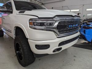 White lifted RAM truck parked indoors next to a blue vehicle