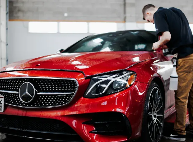 Red Mercedes-Benz being detailed by a worker in a garage
