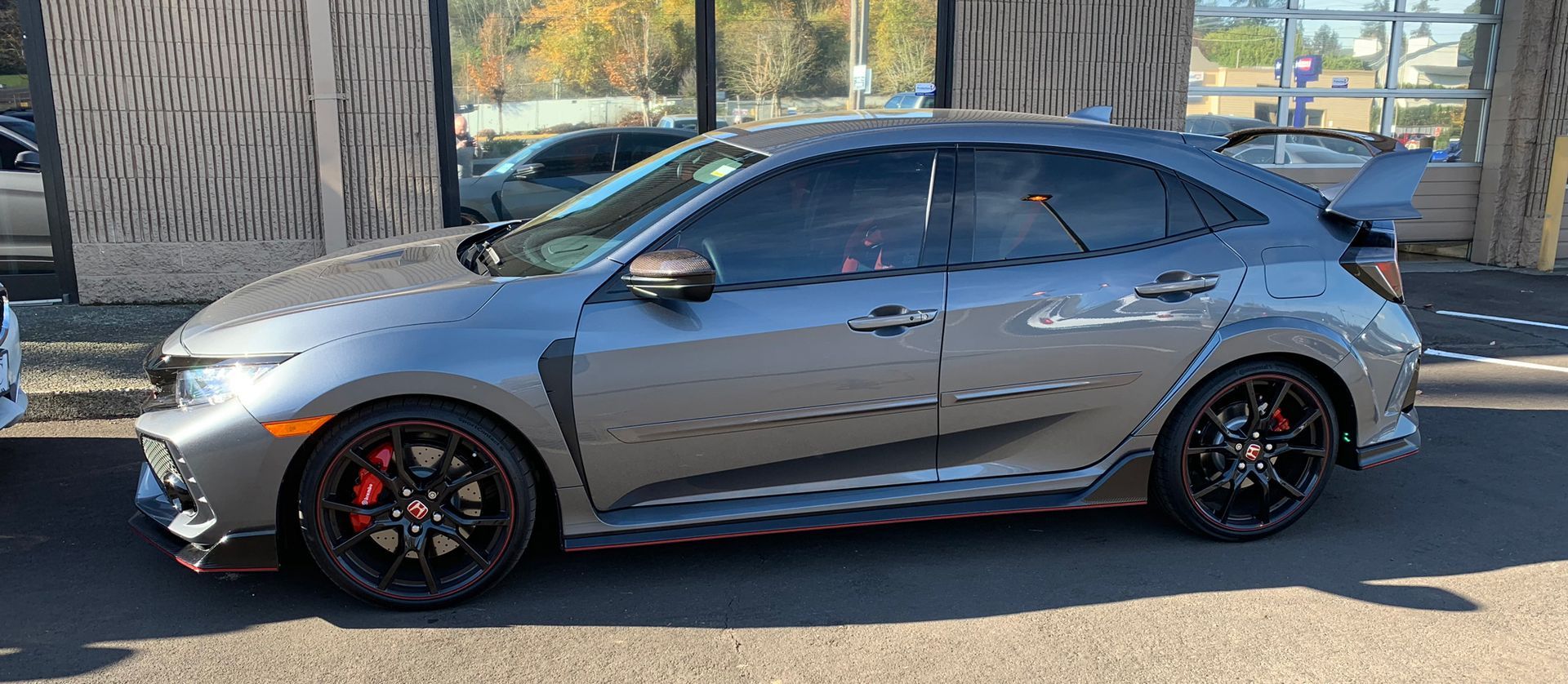 Silver sports sedan parked outdoors in daylight with black wheels and tinted windows