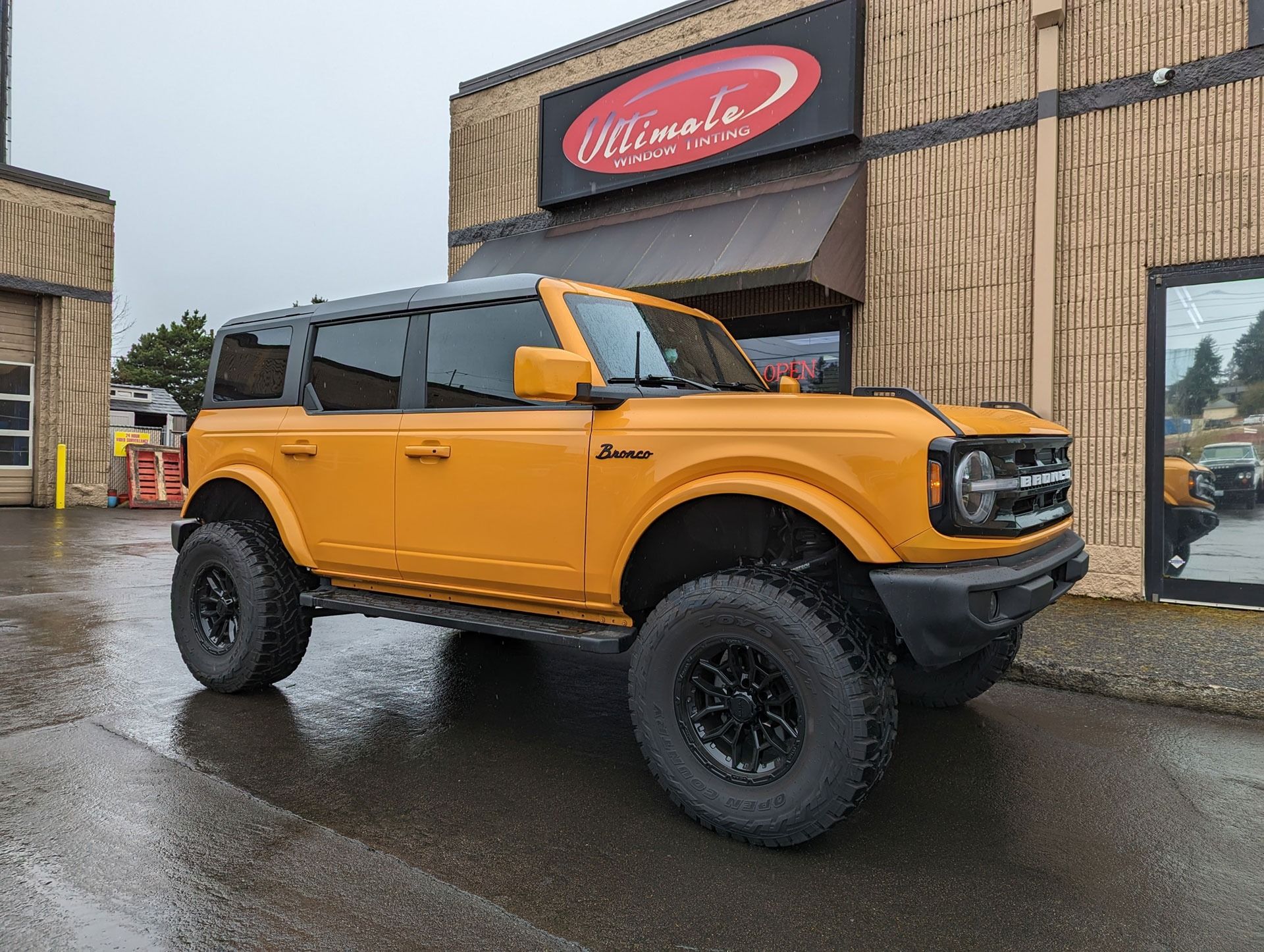 Bright orange off-road SUV parked outside a building on a wet street