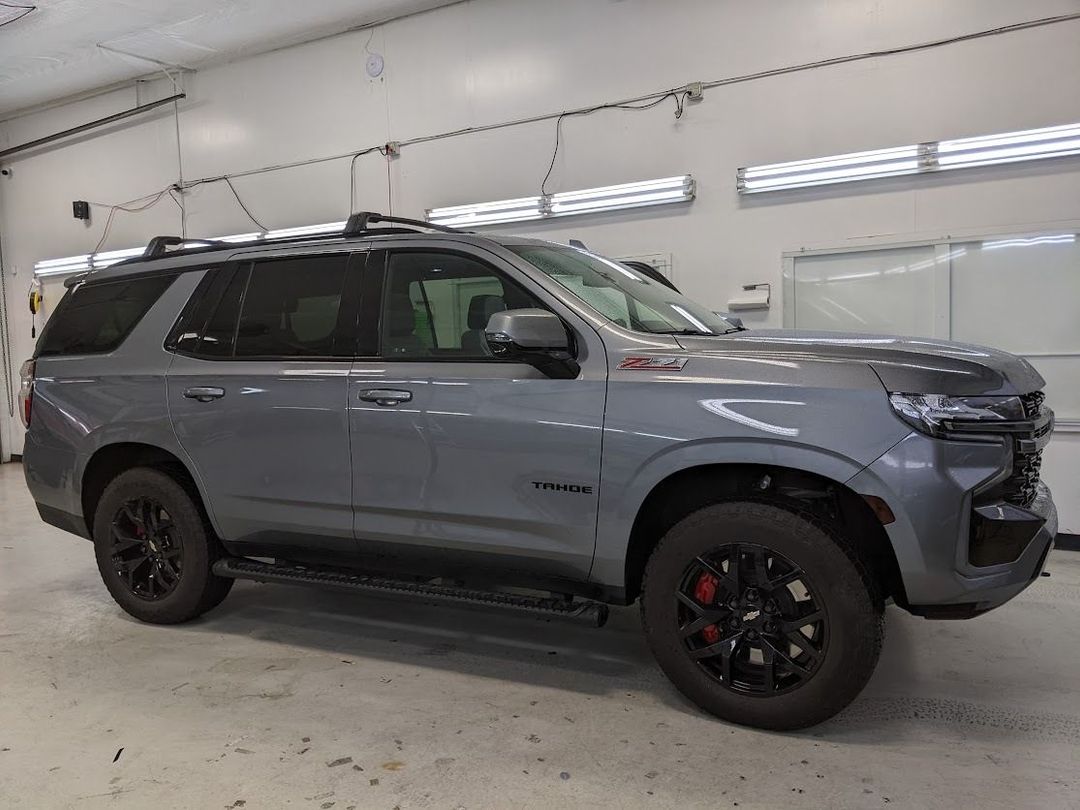 Gray SUV parked indoors in a garage-like space, with black wheels and red brake calipers.