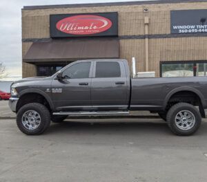 Dark gray lifted pickup truck parked in front of a storefront