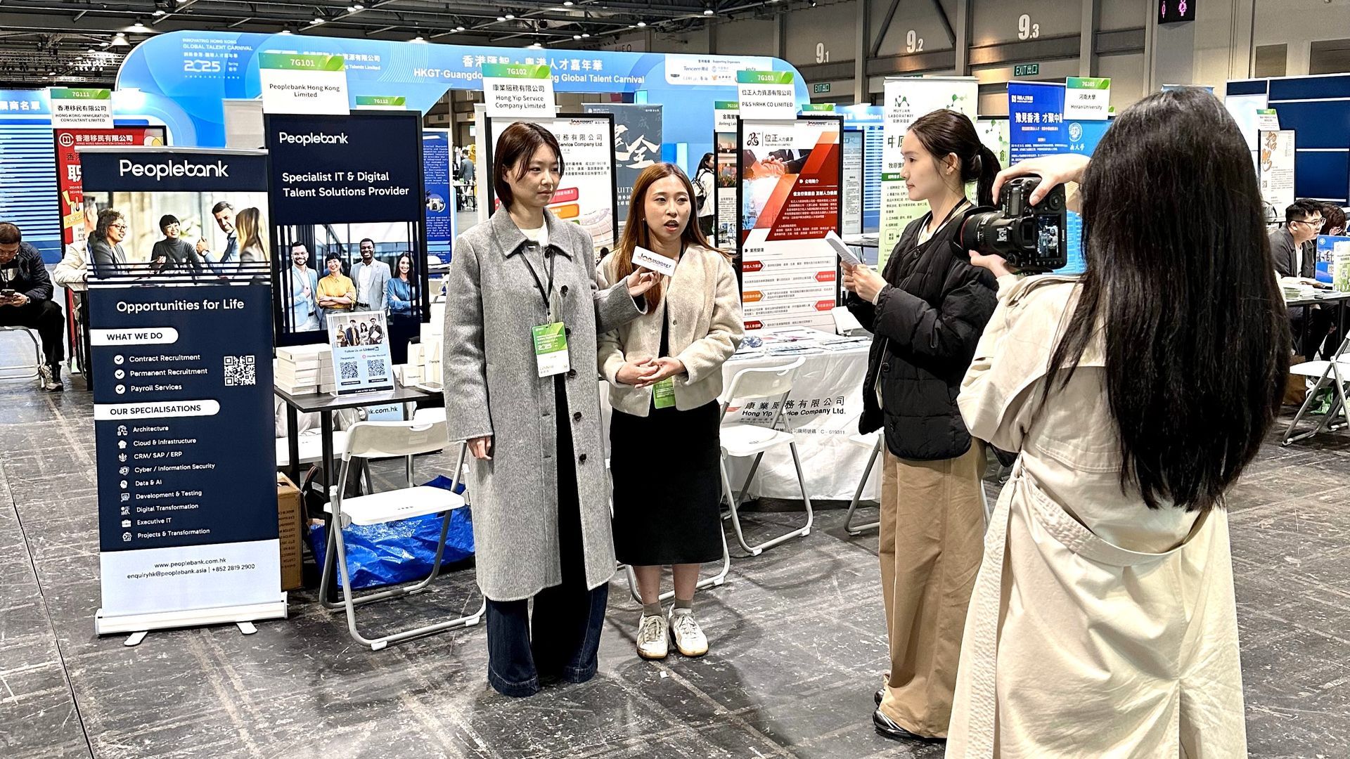 A woman is taking a picture of a group of women at a convention.