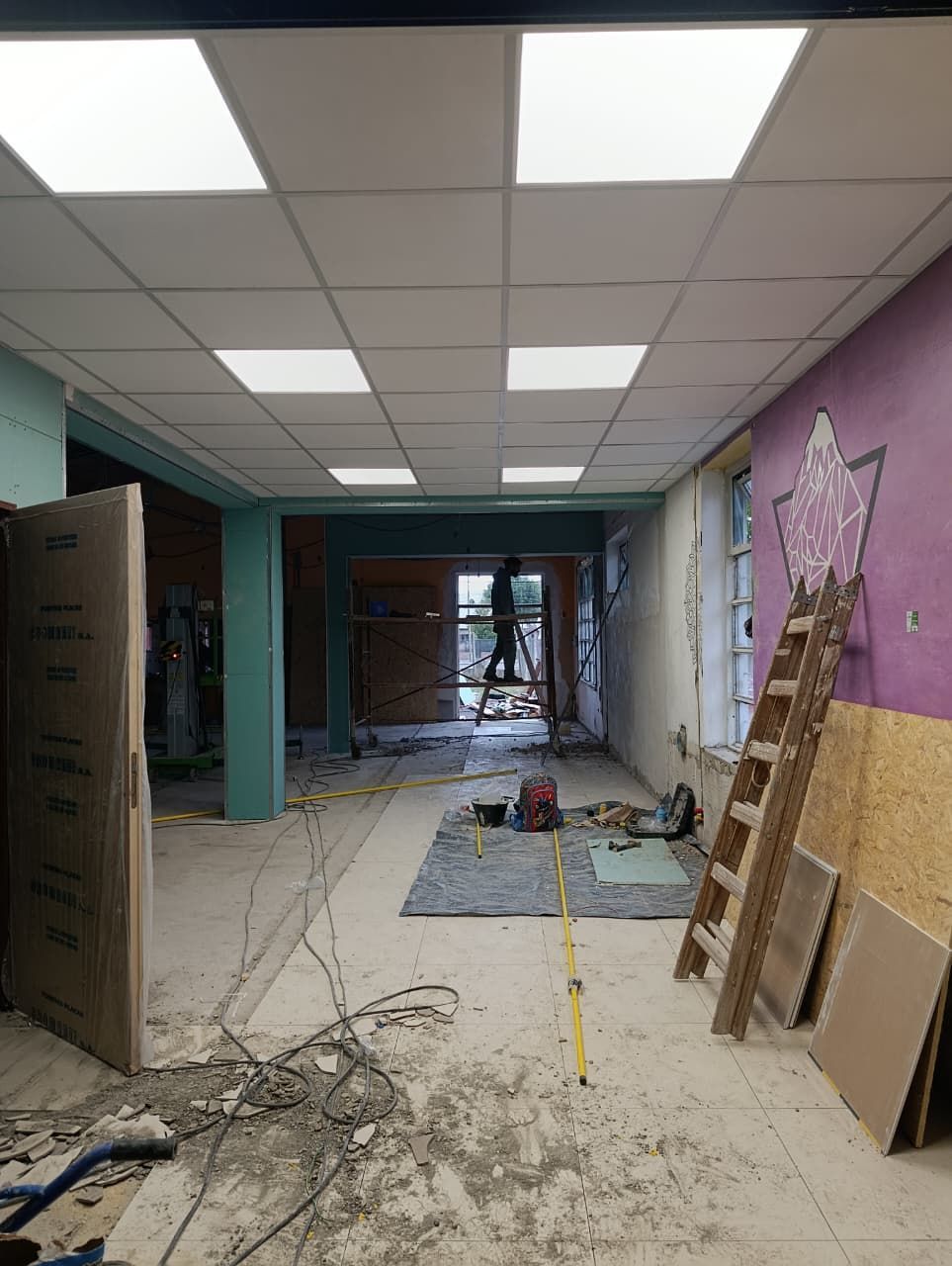 Obras de renovación en un pasillo con baldosas de techo a la vista