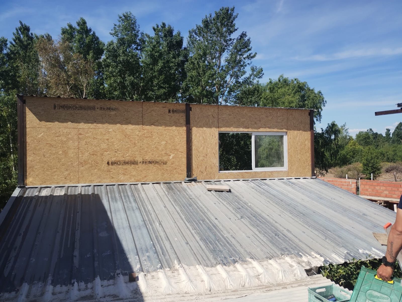 Techo parcialmente terminado con láminas de metal corrugado y un pequeño muro de construcción en construcción.